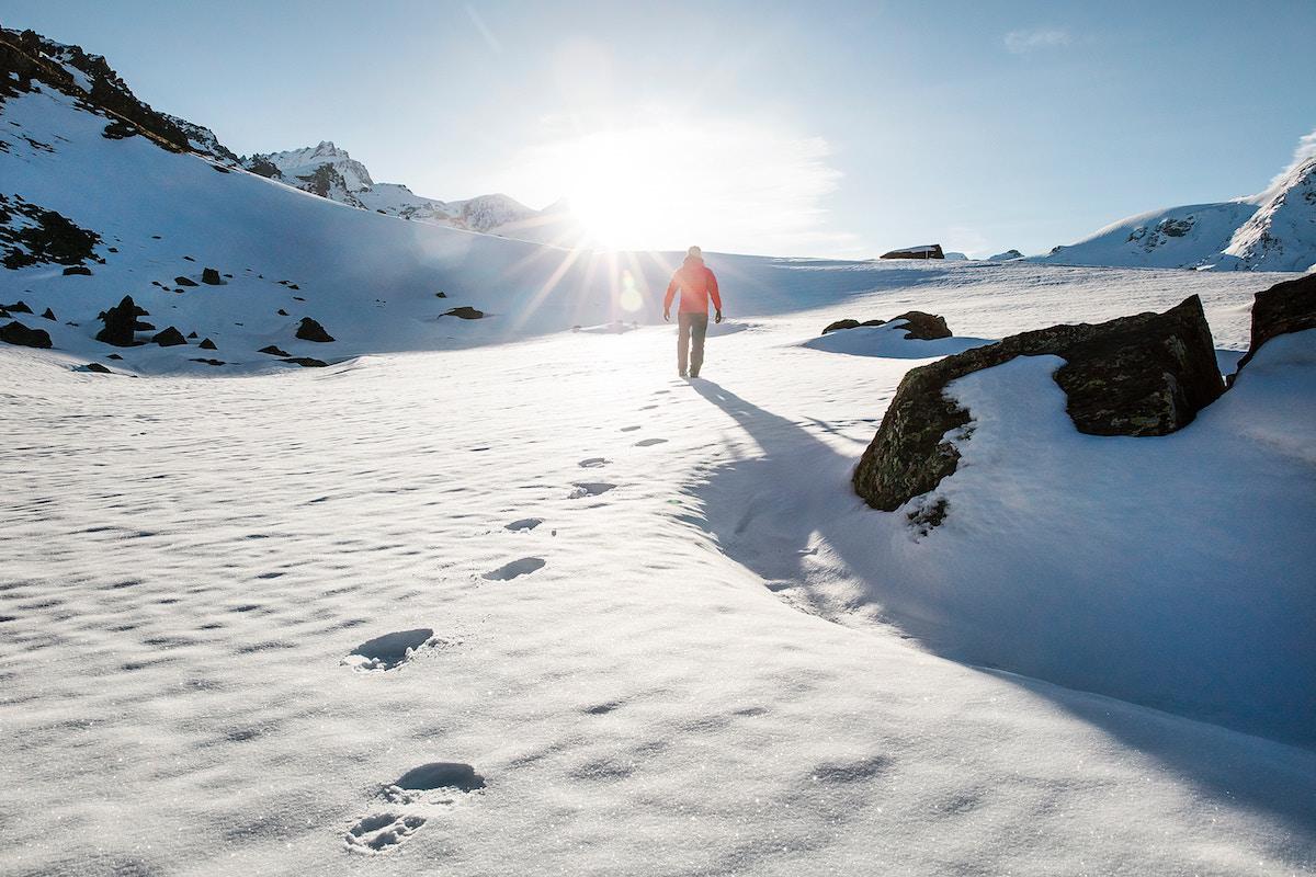 Mountaineer walking through the snow into the sun
